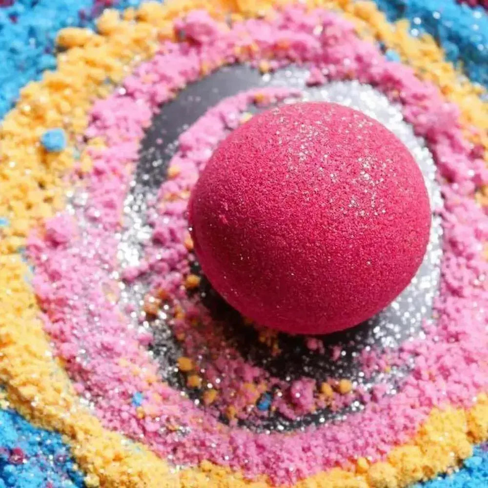 Vibrant pink bath bomb surrounded by colorful, glittery bath bomb dye powder for creative crafting.