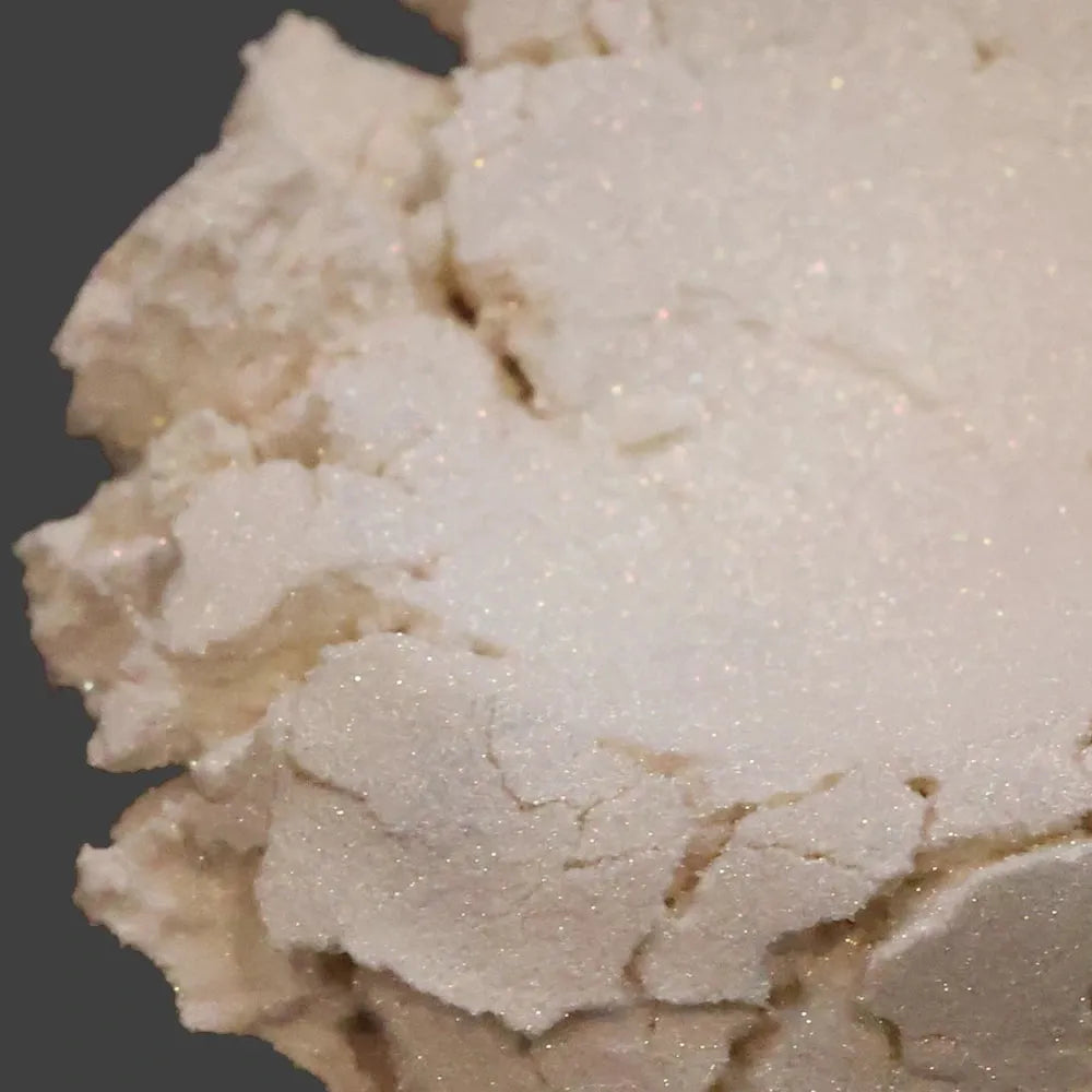 Cream white mica powder with gold shimmer on dark background