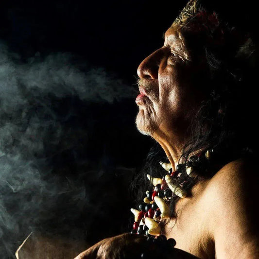 Elder exhaling smoke in a mystical ambiance, adorned with tribal jewelry, embodying spiritual essence.