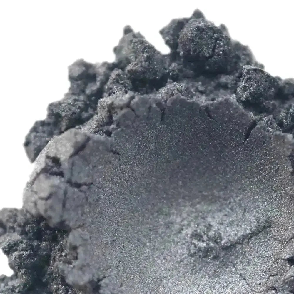 A close-up of a rough, metallic, dark gray crystal with a shiny surface and jagged edges, inspiring for soap makers using Neutral Gray Mica.
