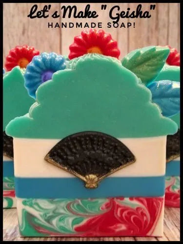 Colorful handmade 'Geisha' soap with floral design and fan detail, showcasing unique artistry in soap making.