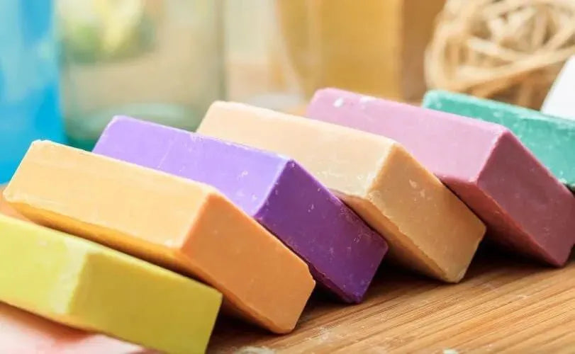 Colorful soap bars arranged on a wooden surface, showcasing different hues and textures.