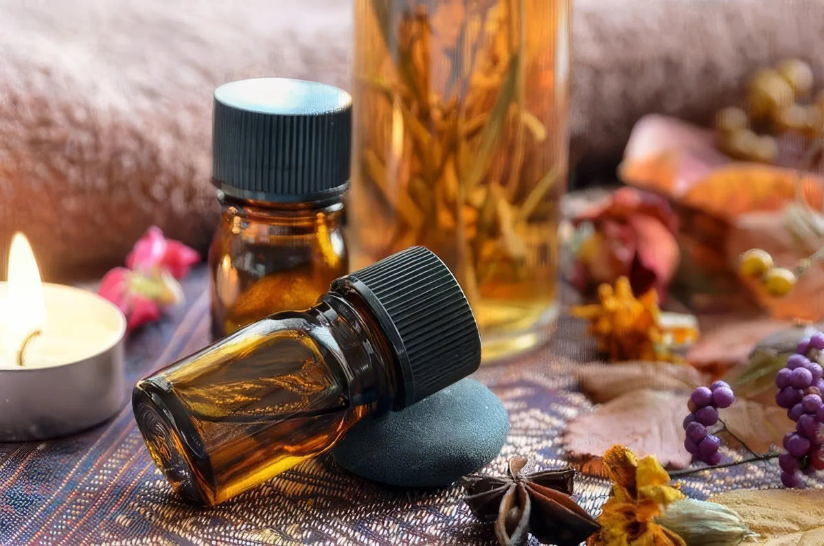 Amber essential oil bottles beside lit tealight, autumn leaves and berries