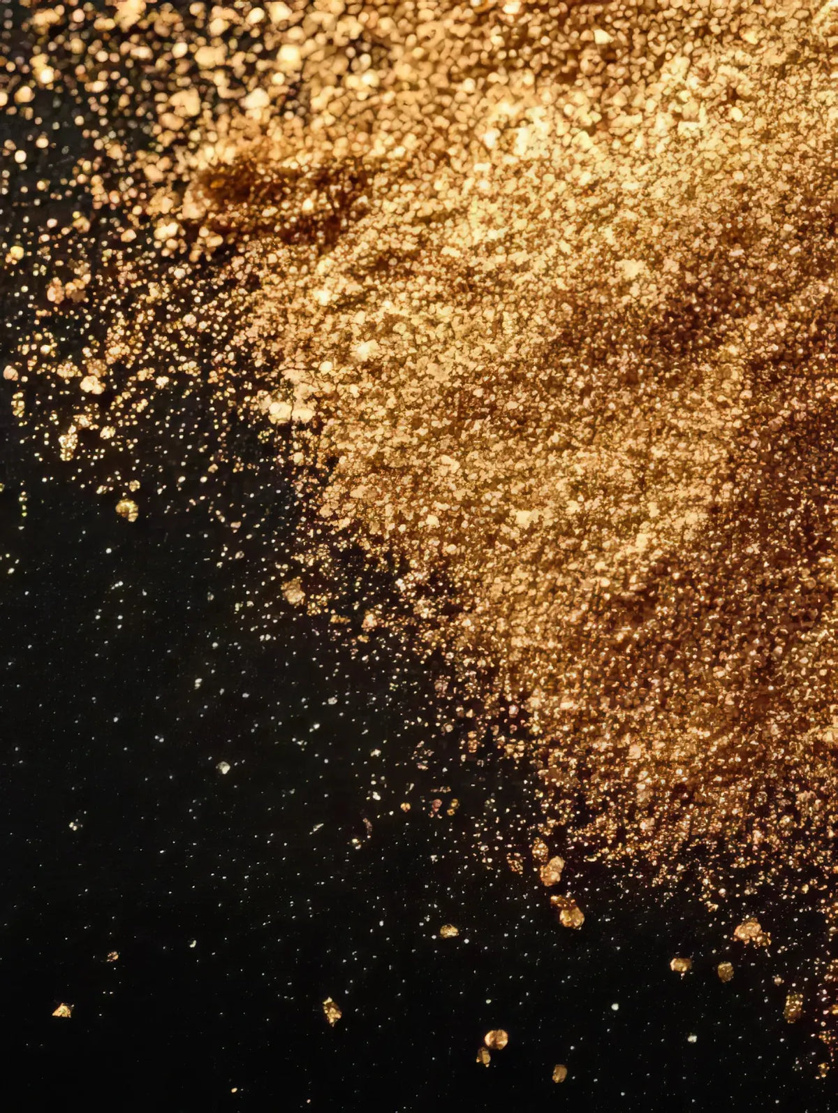 Gold shimmer mica powder scattered across a black background