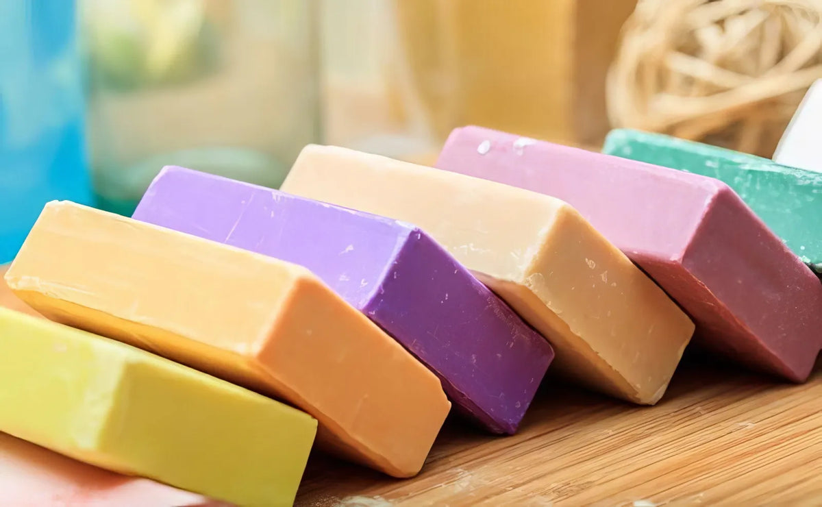 Colourful soap bars in a row on wooden cutting board