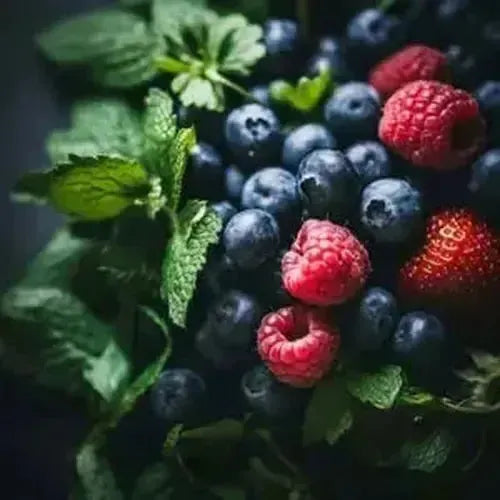 Fresh mixed berries with mint leaves, including raspberries, blueberries, and strawberries, on a dark background.