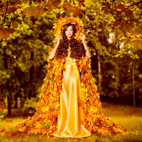 Woman in an autumn-themed dress made of golden leaves standing in a forest.