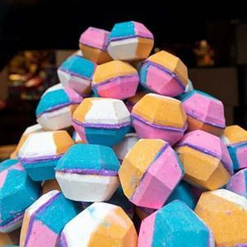 Colorful bath bombs stacked high, showcasing vibrant hues of pink, blue, orange, and white for luxurious bath experiences.