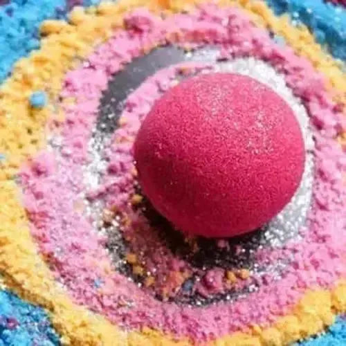 Bright pink bath bomb surrounded by colorful bath bomb fizz and glitter, perfect for a relaxing soak.
