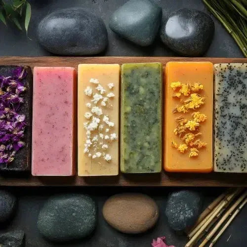Colorful melt and pour soap bars with floral accents on a wooden tray and smooth stones.