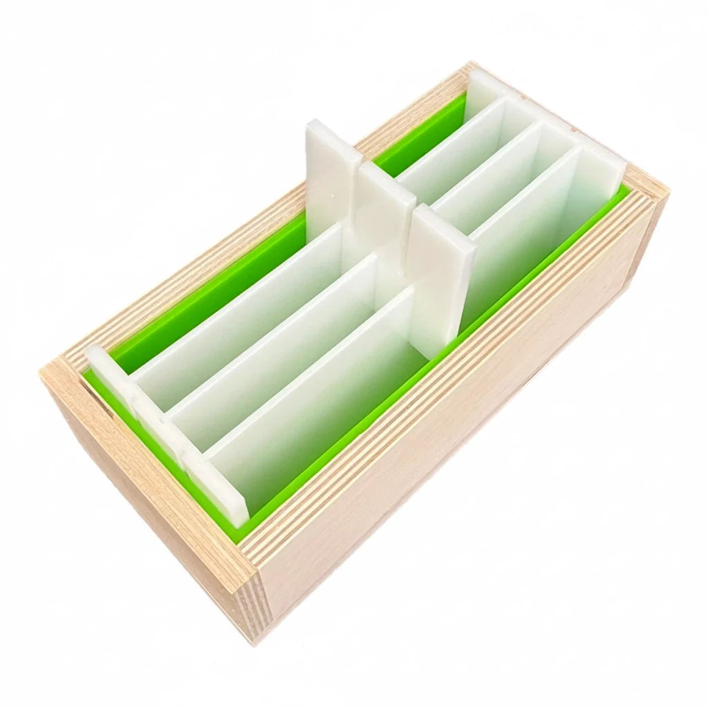 Light-colored wooden soap mold with green silicone inserts and white dividers, nurturesoap brand.