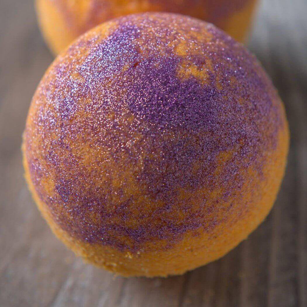 Handmade bath bomb with shimmering purple and orange colors by Nurture Handmade.