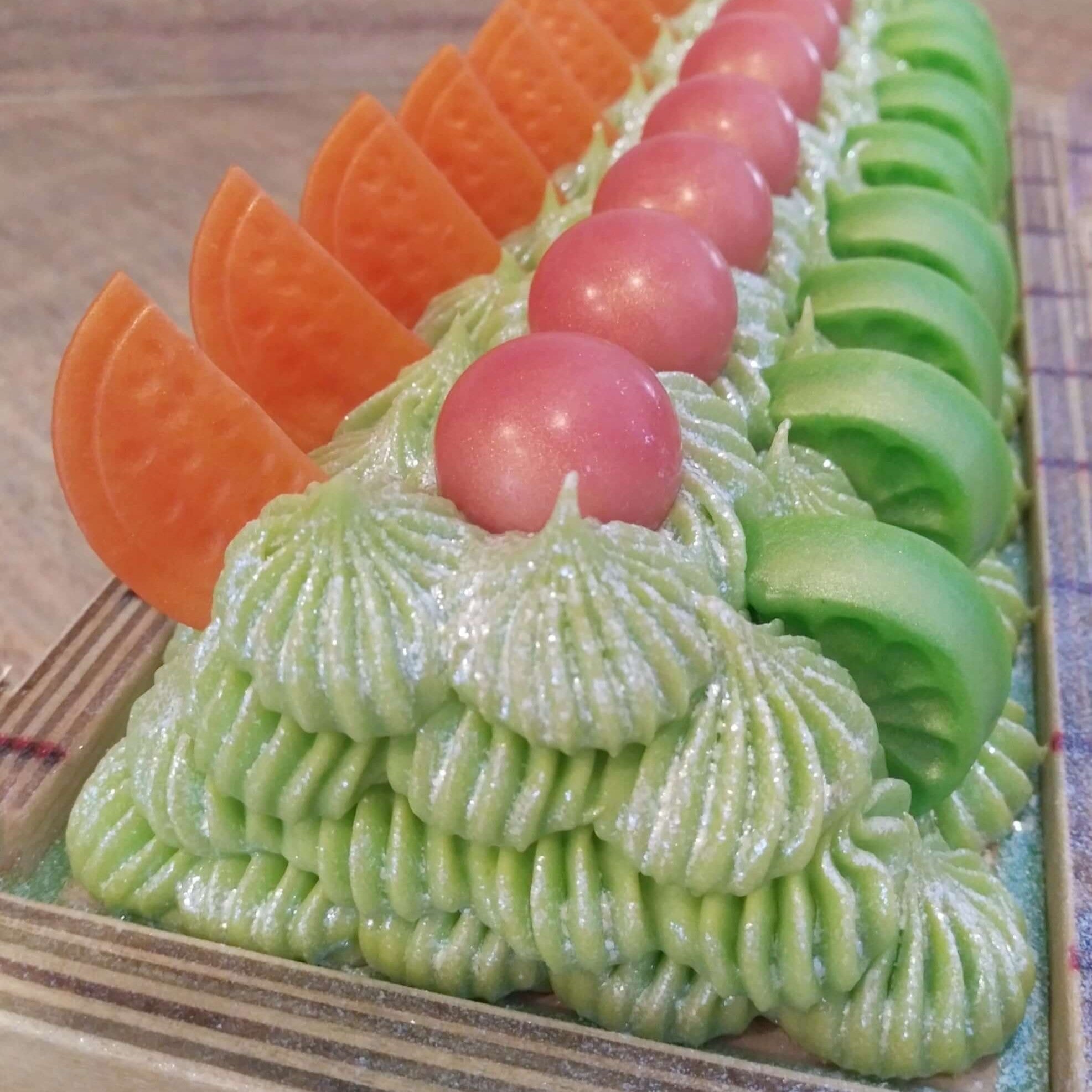 Decorative soap with green icing, orange and pink elements on a wooden surface