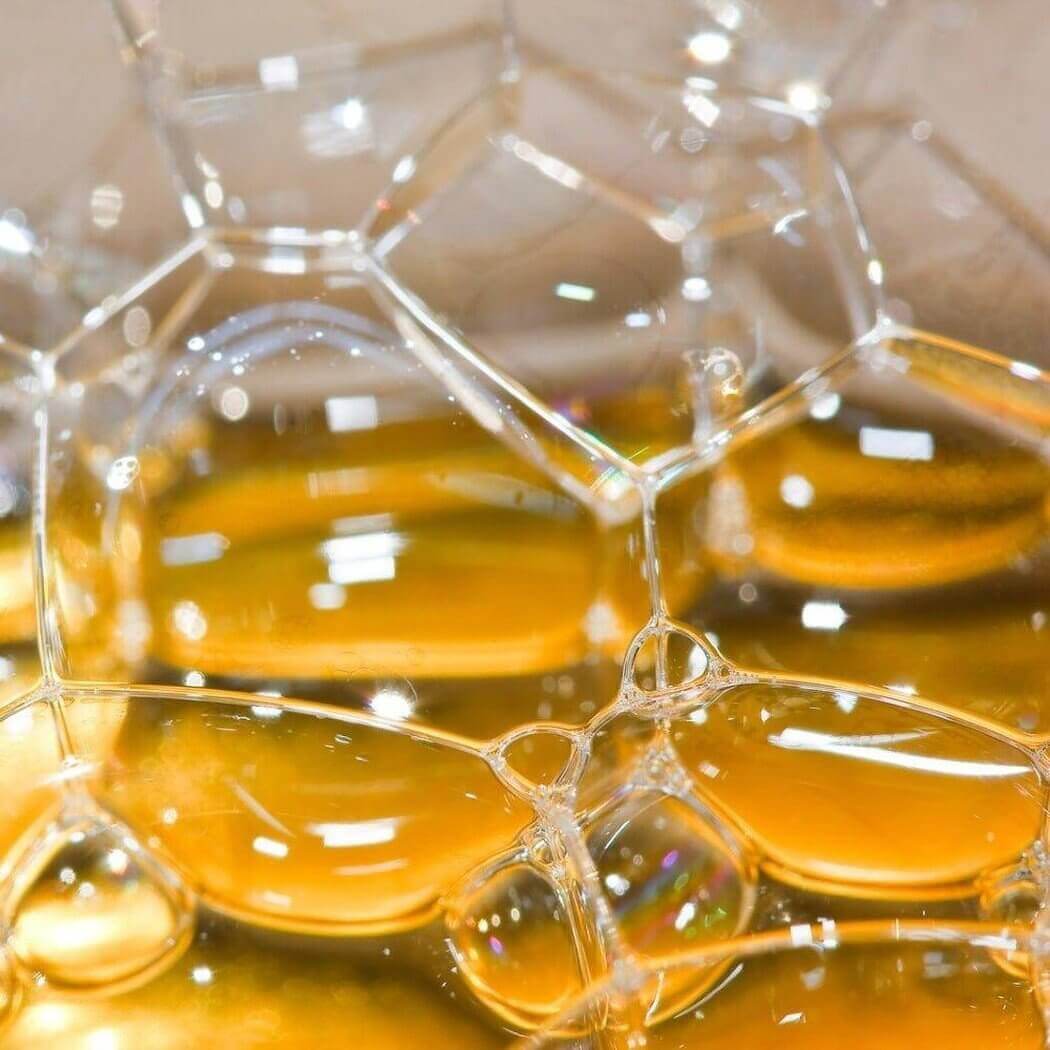 Close-up shot of golden-hued soap bubbles with reflective surfaces representing Nurture Handmade natural skincare products.