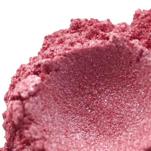 Close-up of shimmering pink handmade cosmetic powder, showcasing its texture and sparkle. Nurture Handmade beauty product.