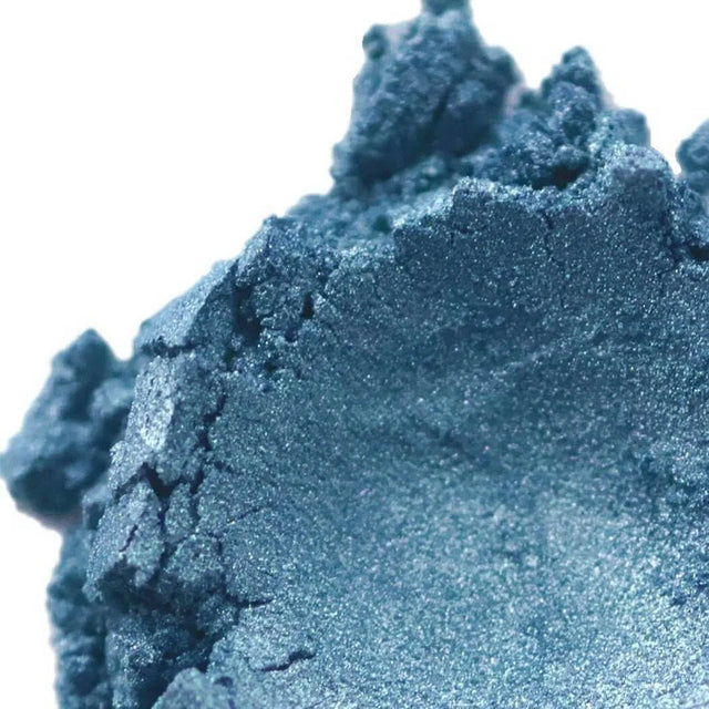 Close-up of vibrant blue mineral eyeshadow pigment showcasing its shimmery texture and rich color.