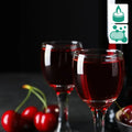 Two clear glass wine glasses with red Black Cherry Merlot fragrance oil and fresh cherries