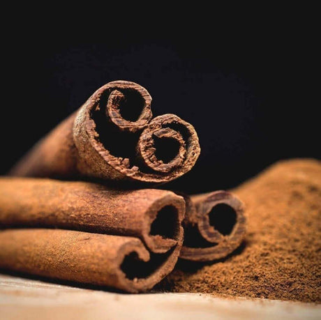 Close-up of aromatic cinnamon sticks and ground cinnamon on a dark background, showcasing natural spice elements.