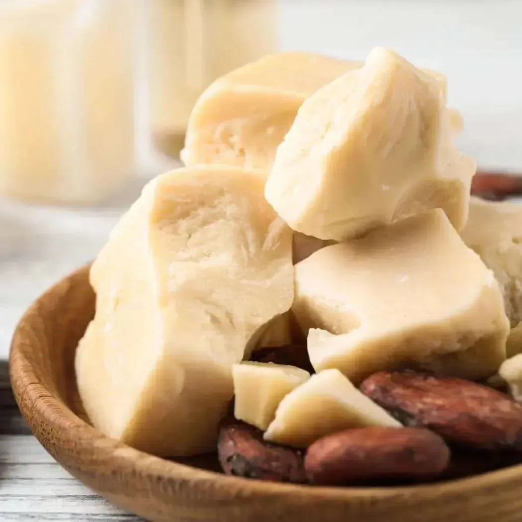 Creamy off-white shea butter blocks in wooden bowl with cocoa beans for Cocoa Butter Cashmere Fragrance Blend