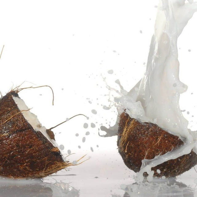 Splitting coconuts with milk splash, showcasing nature's nurture, handmade refreshment.