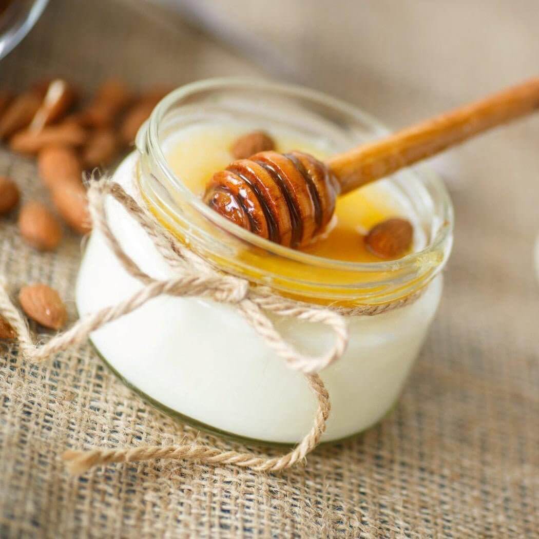 Handmade honey and almond yogurt in a glass jar with rustic twine, emphasizing natural and nurturing ingredients.