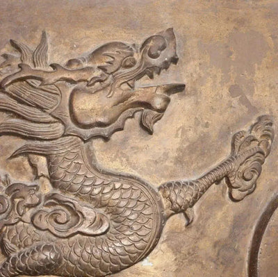 Carved bronze relief of scaled dragon among clouds