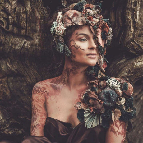 Woman adorned with floral and foliage headpiece, earthy theme.