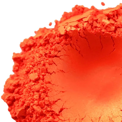 Mound of bright orange red mica powder on white