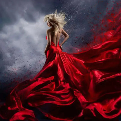 Blonde woman in flowing red satin gown against stormy grey sky