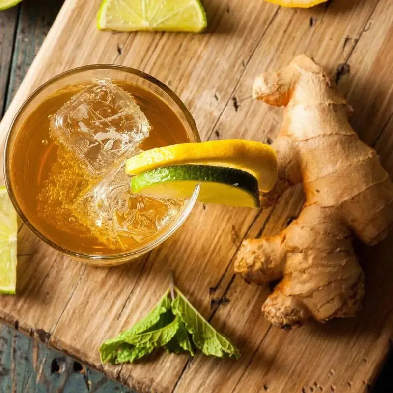 Iced amber drink with lime and ginger root on board