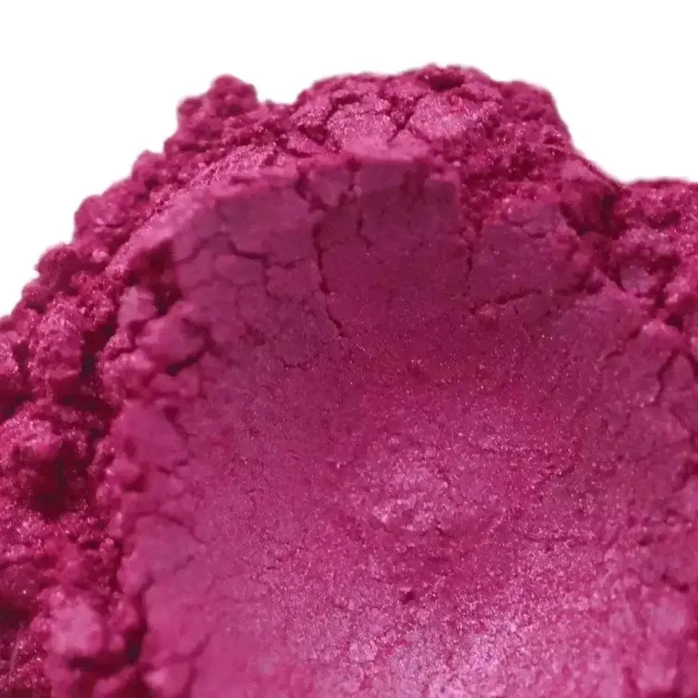 Close-up of Hollywood Pink Mica, showcasing vibrant magenta tones with pink and purple hues, a slightly cracked uneven surface, and a small central indentation.