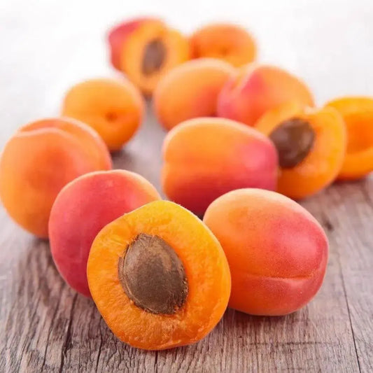 Fresh, juicy apricots sliced in half, showcasing their sweet, vibrant flesh and pit on a rustic wooden background.