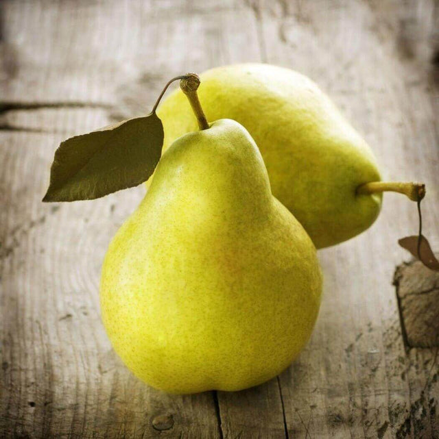 Fresh yellow pears with leaves on a rustic wooden table.