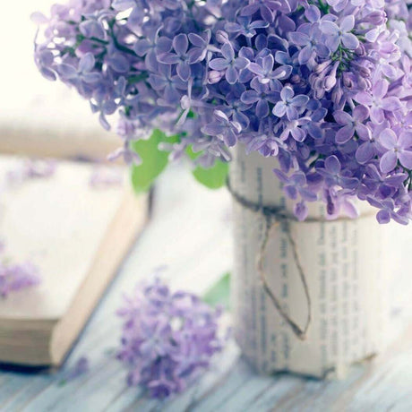 Handmade vase with lilac flowers on a wooden table, perfect for nurturing handmade crafts and decor.