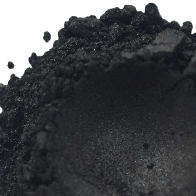 Close-up view of finely ground black powder with a textured surface from Nurture Handmade products.