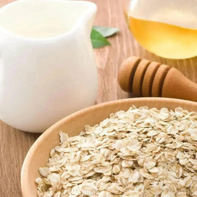 Wooden bowl of rolled oats, milk jug and honey dipper
