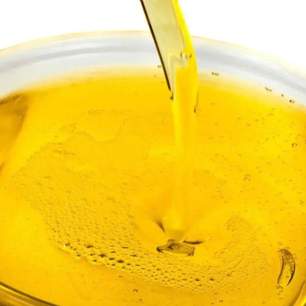 Golden honey from Nurture Soap Making Oil Blend flows into clear bowl