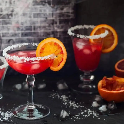 Red citrus cocktails in sugar-rimmed glasses with blood orange slices
