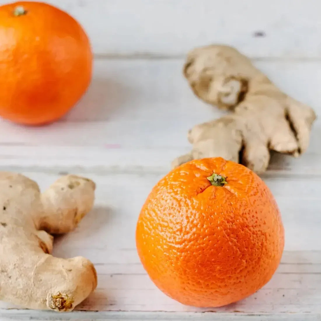 Fresh orange and ginger roots on a wooden surface, highlighting the zesty blend of fragrances.