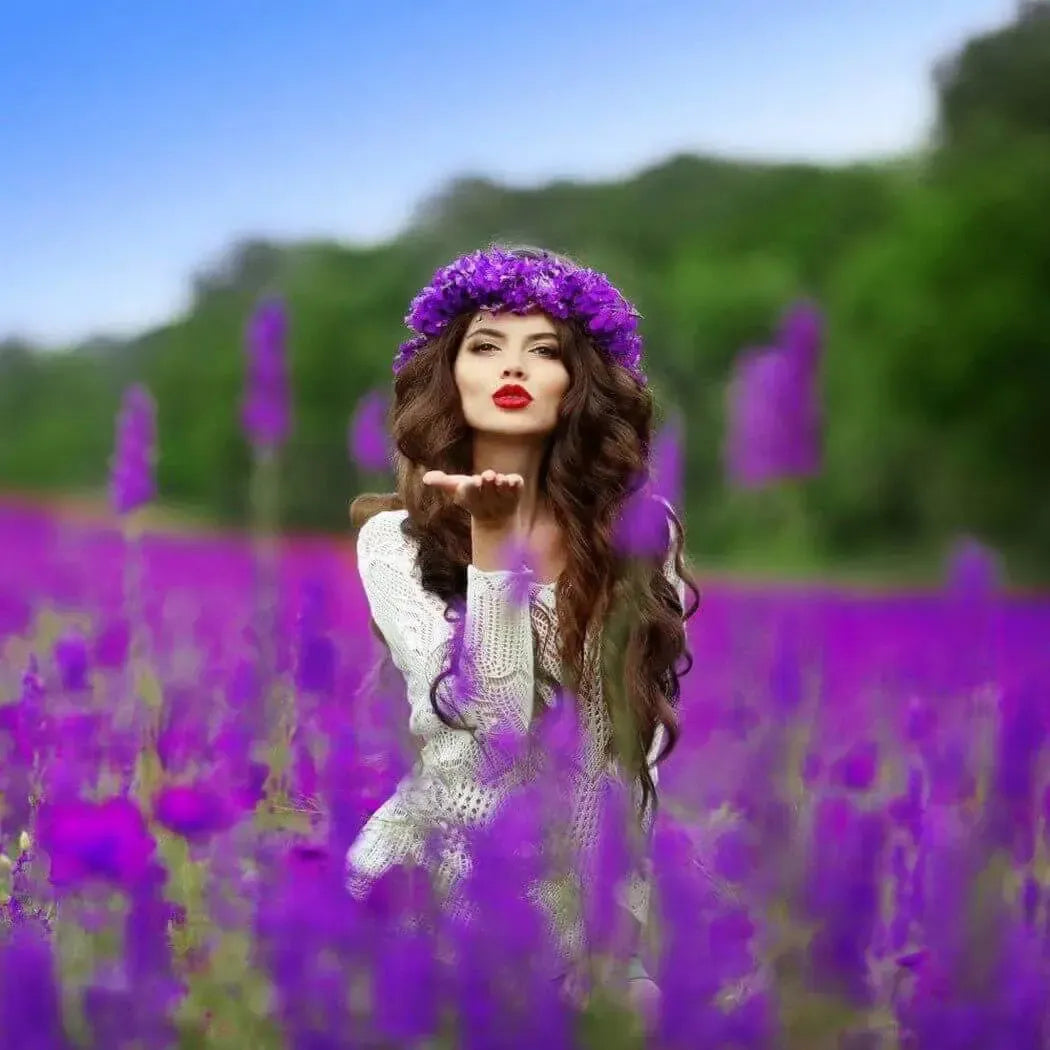 Woman with a flower crown blowing a kiss in a vibrant purple flower field, embodying spring and beauty.