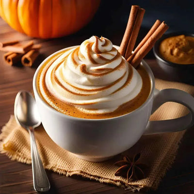 Whipped cream topped latte in white mug with cinnamon sticks, pumpkin behind