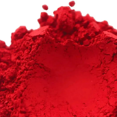 Mound of bright red pigment powder on white background