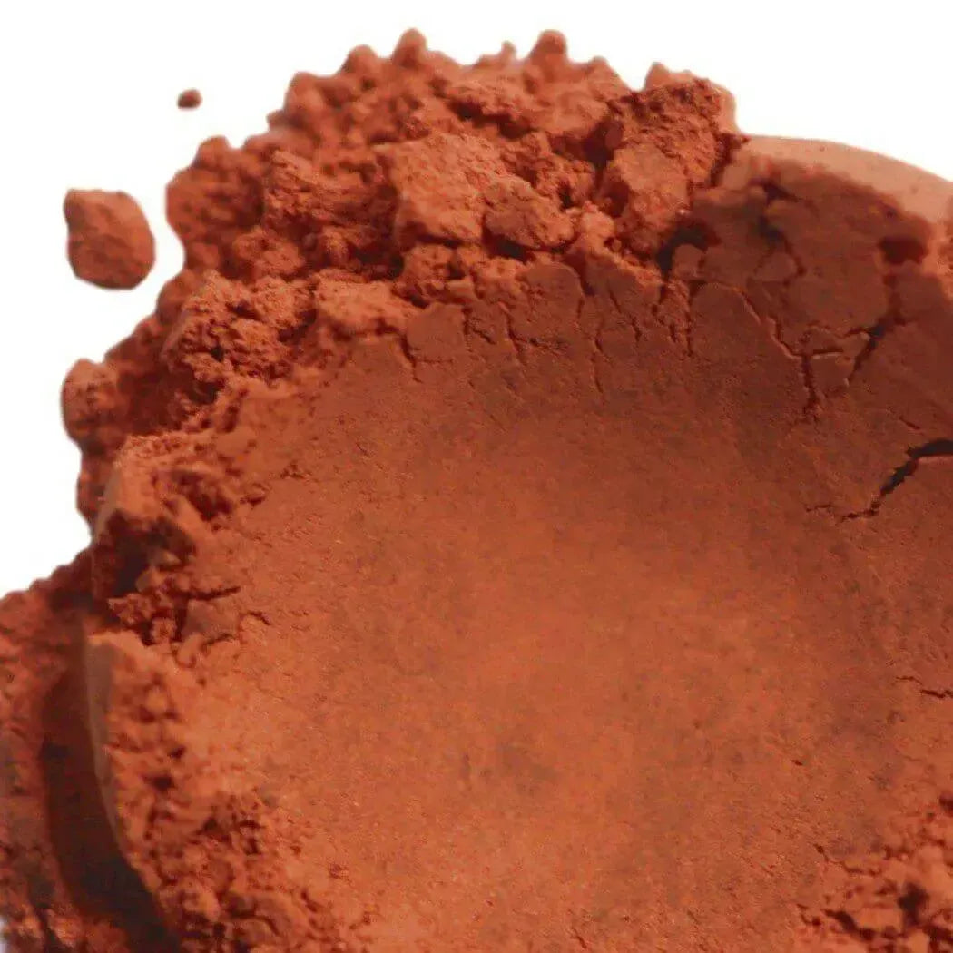 Mound of fine reddish-orange clay powder on white background