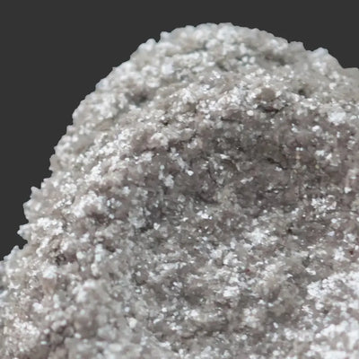 Coarse white powder with sparkling crystals against dark grey background
