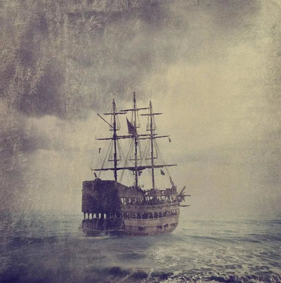 Weathered three-masted sailing ship at sea in grey mist