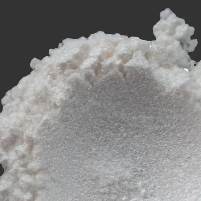 Mound of white sparkling mica powder against black background