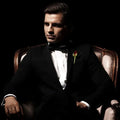 A dapper man in a tuxedo seated elegantly in an armchair, exuding sophistication and charm.