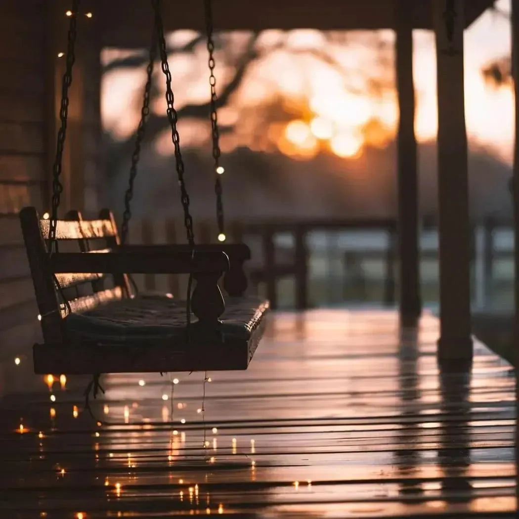 Dark wooden Utopia Fragrance Blend porch swing with cushioned seat and warm lights