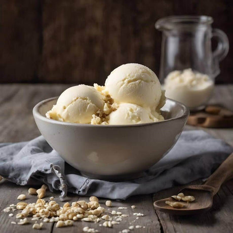 Bowl of handmade vanilla ice cream topped with nuts, with a jar of milk in the background on a rustic wooden table.