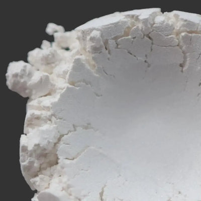Mound of chalky white mica powder against dark grey background
